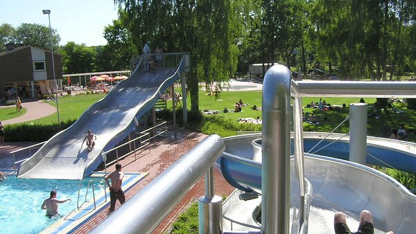 Schwimmbecken mit Badegästen und Wasserrutschen im Waldschwimmbad Bad Bodenteich